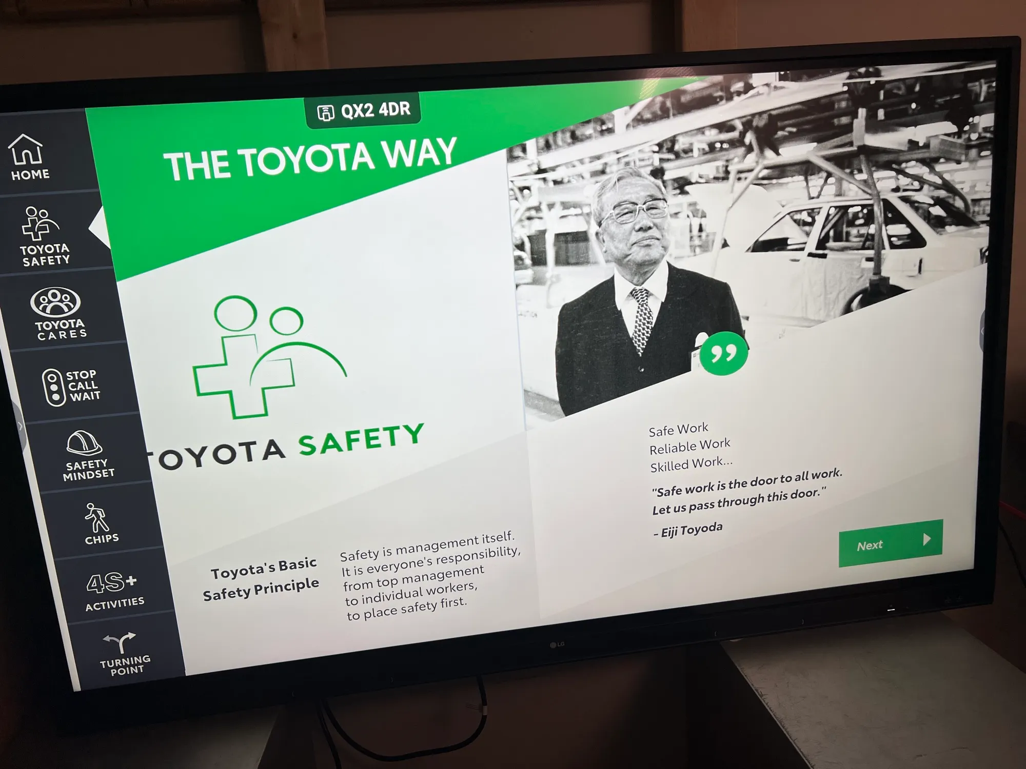 A wall-mounted screen showing "The Toyota Way" module of the training, with the Toyota Safety logo and a portrait of Eiji Toyoda.