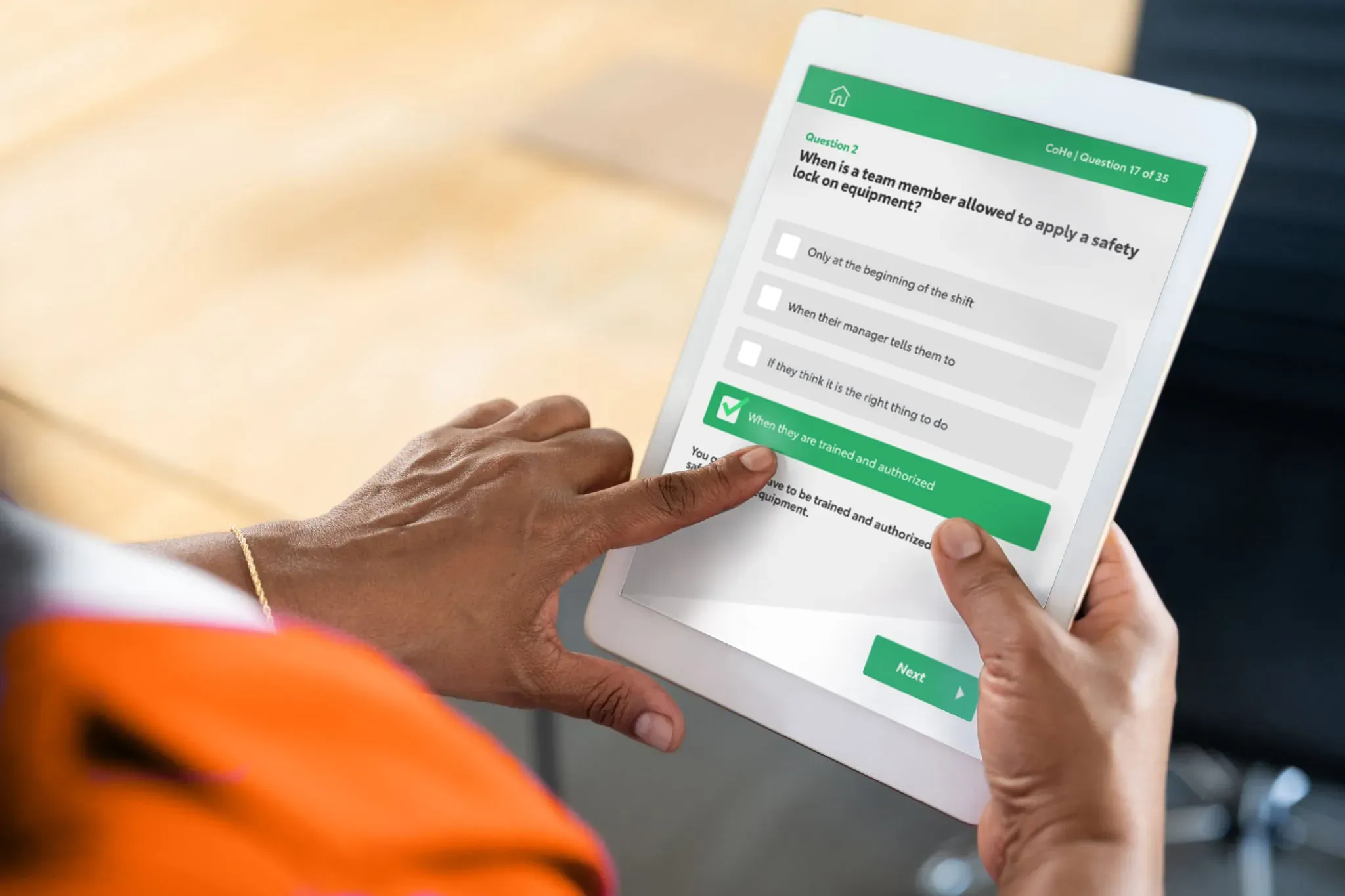A worker in hi-vis holding an iPad and tapping a large green answer button in the Toyota safety quiz app, on question 17 of 35.