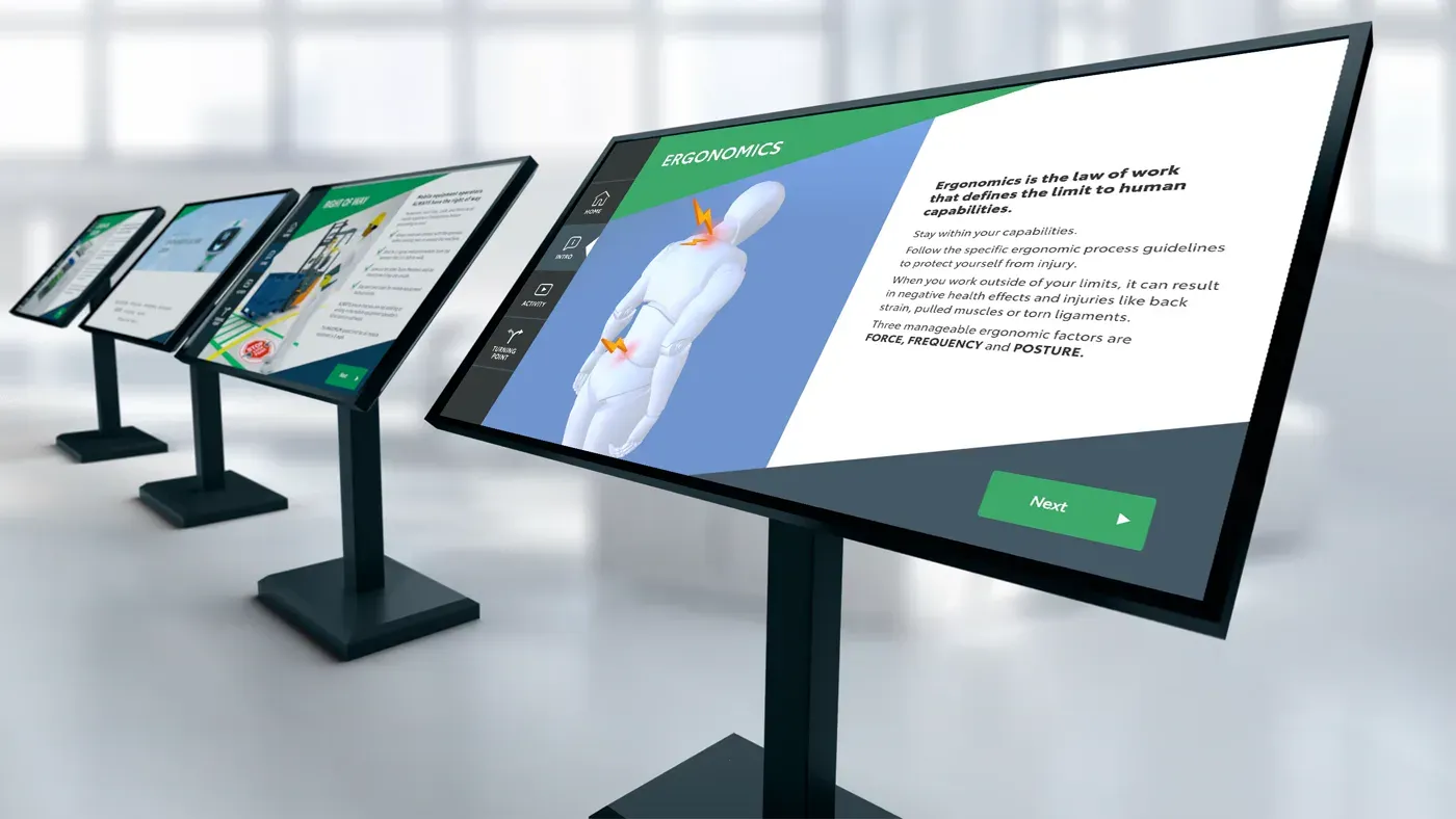 A row of floor-standing 4K touchscreen kiosks running the Toyota training modules, the front one showing the Ergonomics screen.